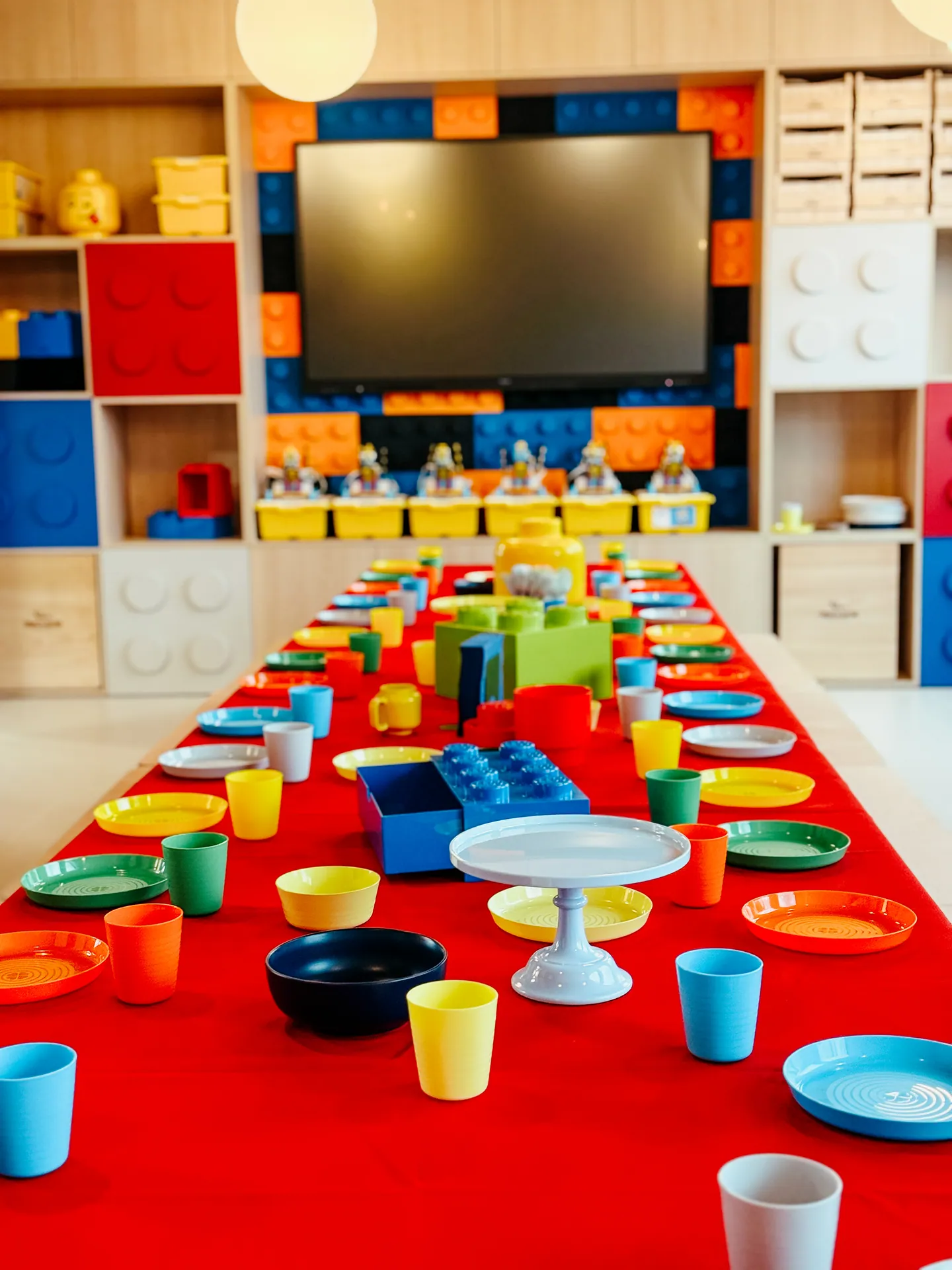 Sala lego — stół urodzinowy z kolorową zastawą i ścianą z klocków