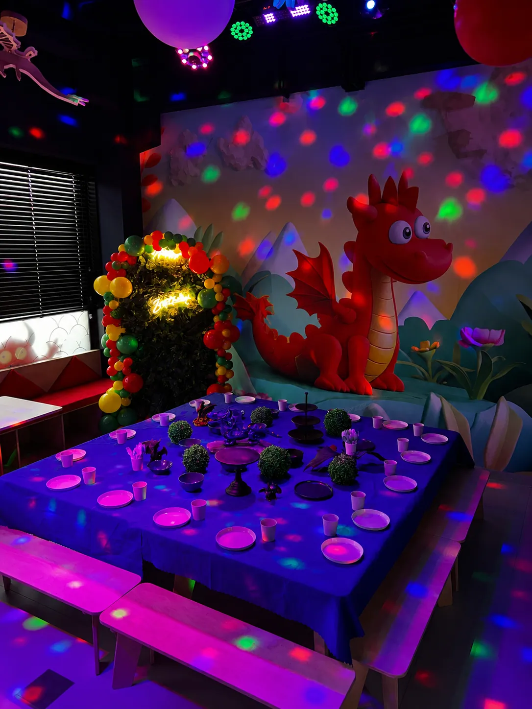 Sala smocza — smok na ścianie i stół urodzinowy w świetle reflektorów
