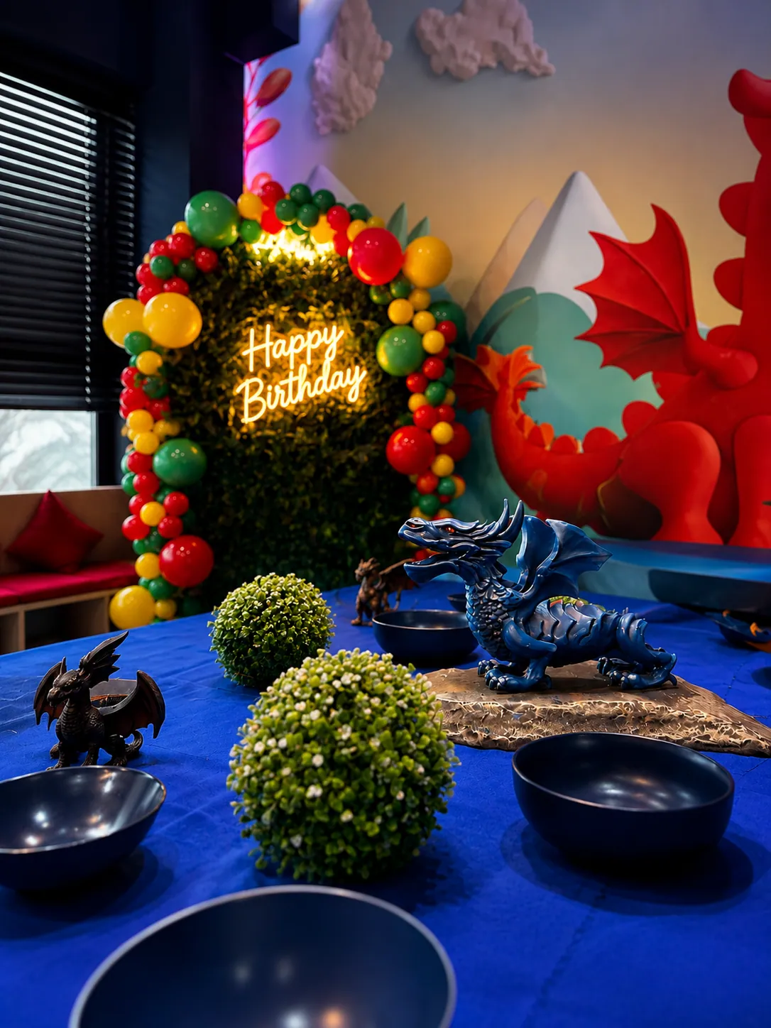 Sala smocza — balonowa brama i neon urodzinowy obok smoka